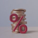 Porcentaje rojo sobre monedas doradas, simbolizando interés financiero o ahorro.