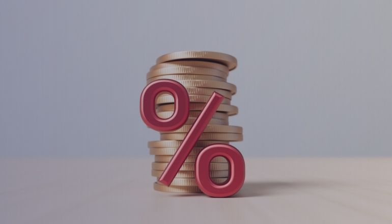 Porcentaje rojo sobre monedas doradas, simbolizando interés financiero o ahorro.