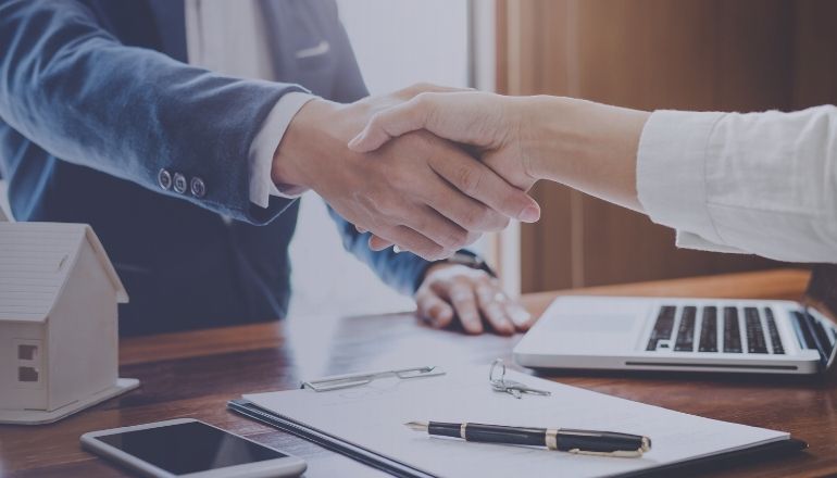 Acuerdo de compra de casa con llaves y contrato en escritorio.