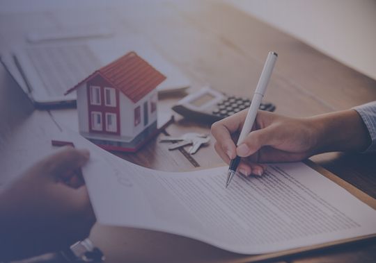 Firmando contrato de compra venta de casa con modelo inmobiliario y llaves en escritorio